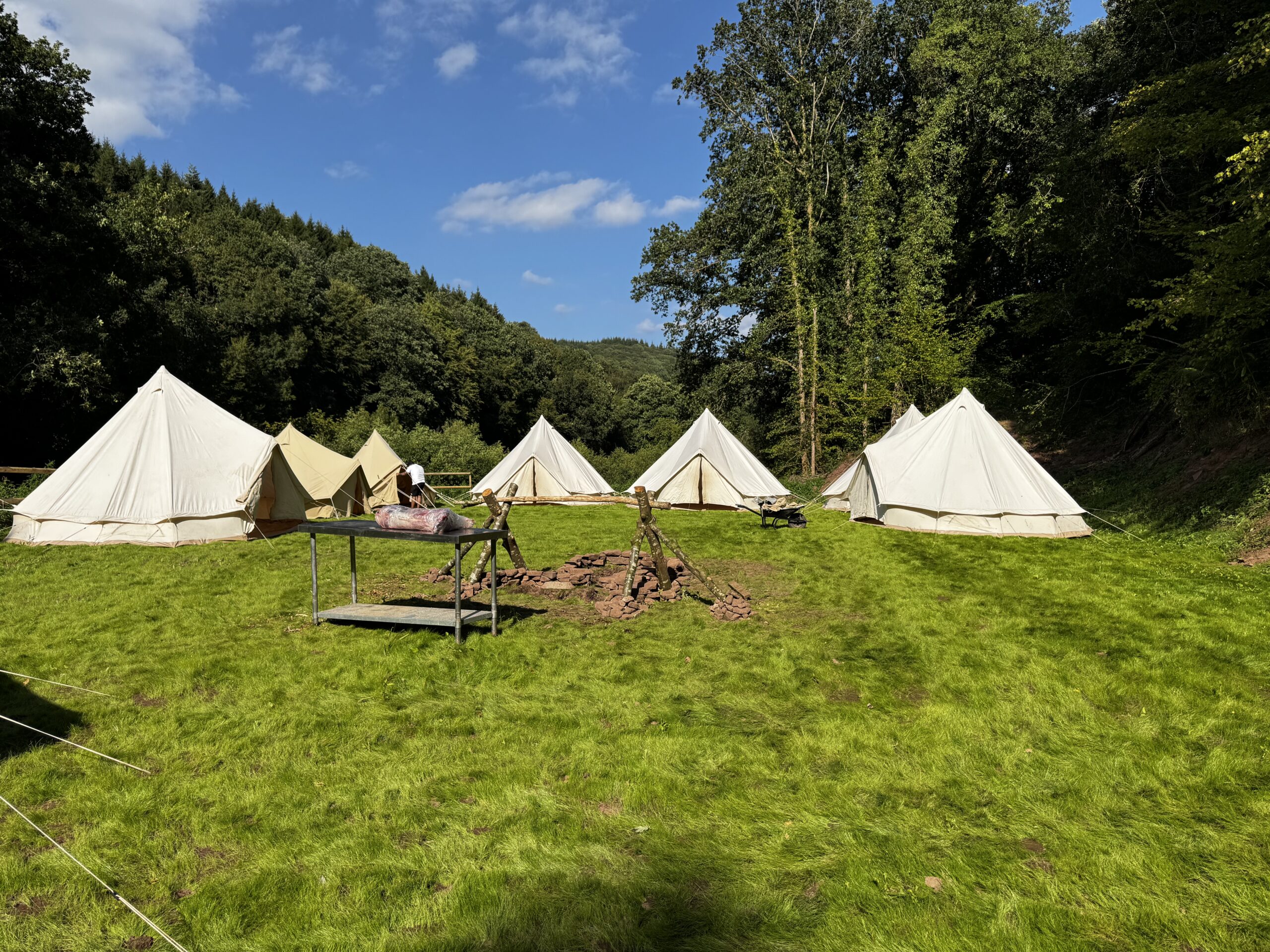 A field containing seven tents arranged in a circle around a fire pit.